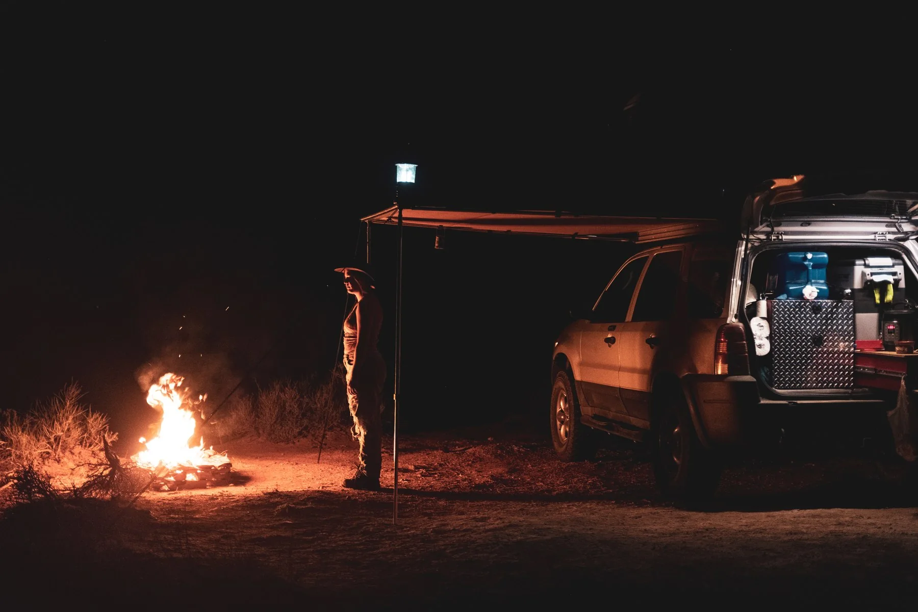 The Ford Escape and awning beside a campfire under the night sky