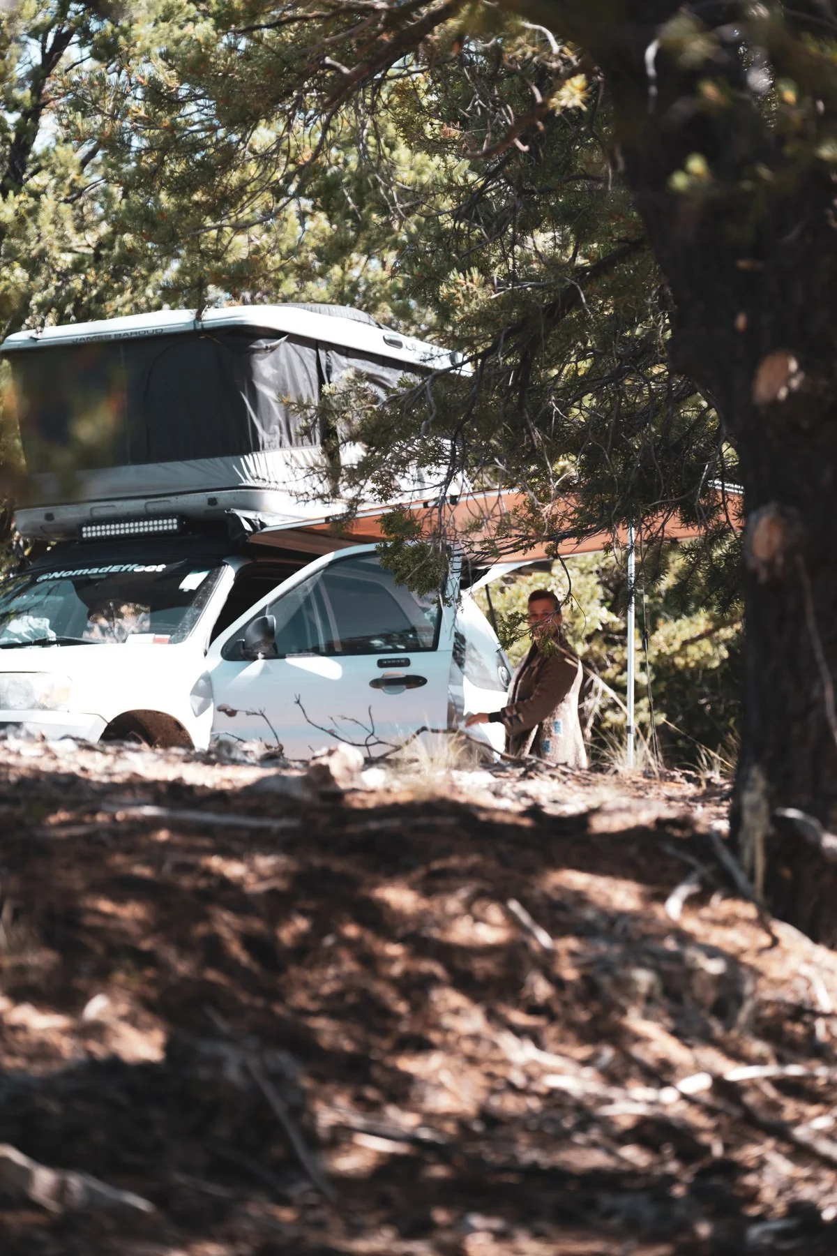 Our Ford Escape with its rooftop tent open in a wooded campsite